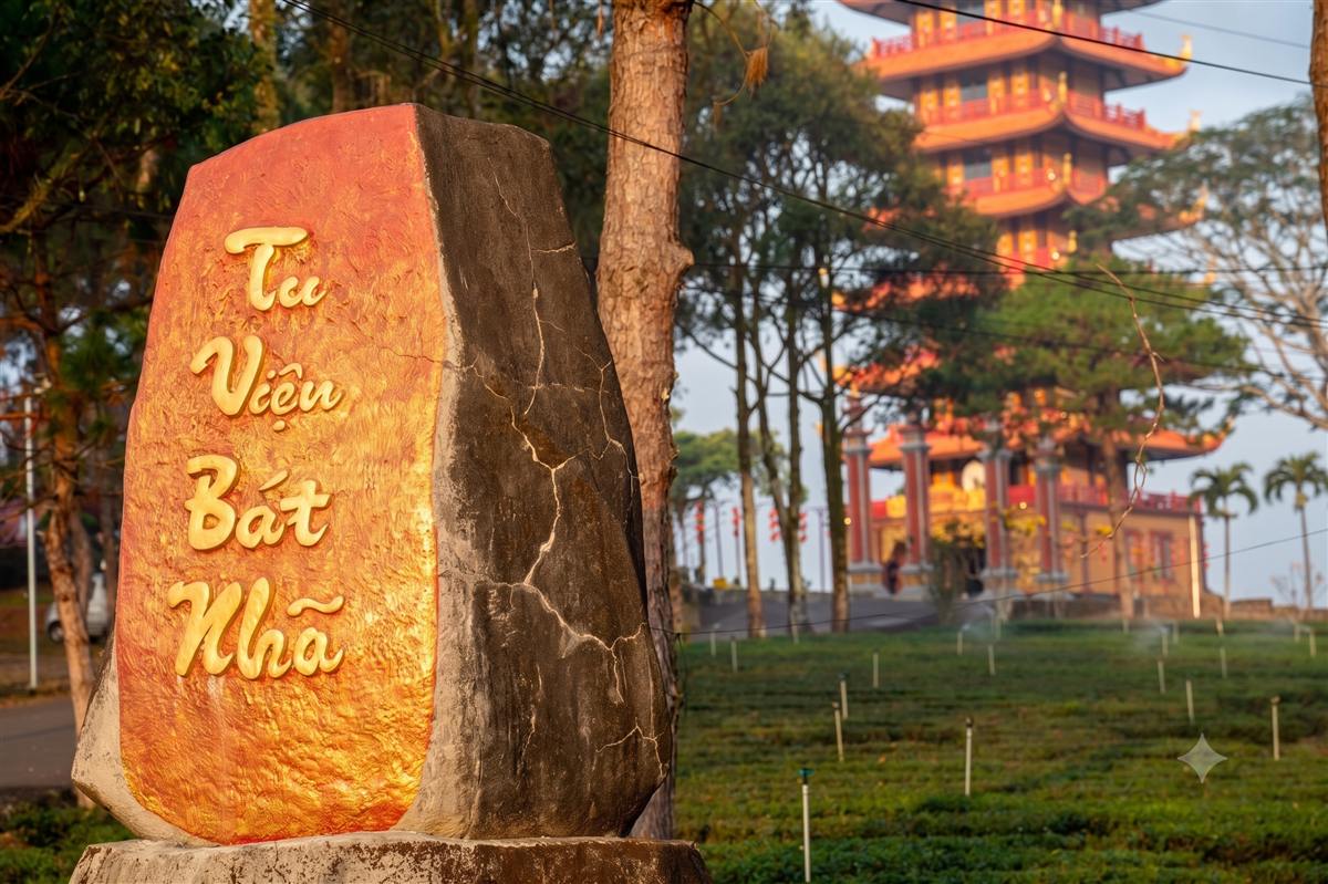 Khối đá khắc chữ Bát Nhã ở lối vào phụ, phía sau là bảo tháp và đồi chè