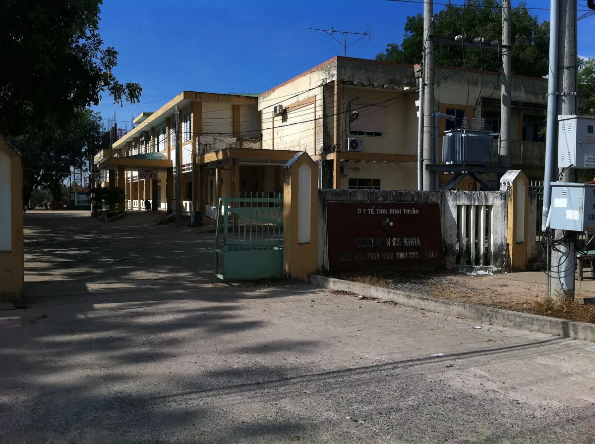 Dãy nhà y tế thấp tầng chạy dài ven đường, có mái che lối đi và biển hiệu trước cổng