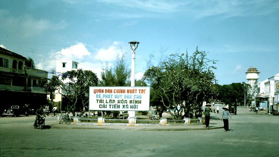 Vòng xoay trung tâm Phan Thiết năm 1967 với hai người đội nón lá và tháp nước phía xa