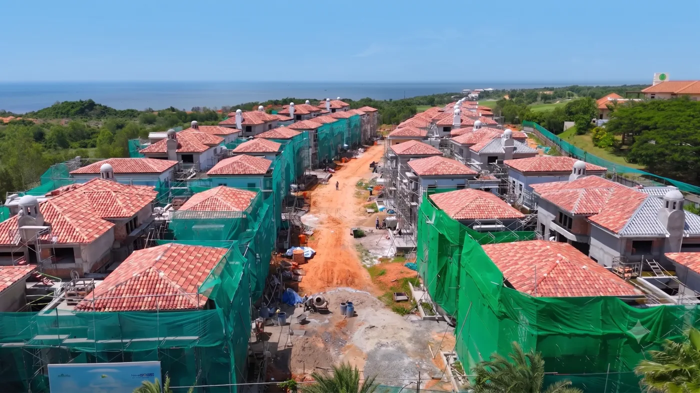 Ảnh từ trên cao hai dãy biệt thự VIP Ocean Villa mái ngói đỏ đã lợp xong, quanh tường phủ lưới xanh, phía xa là biển