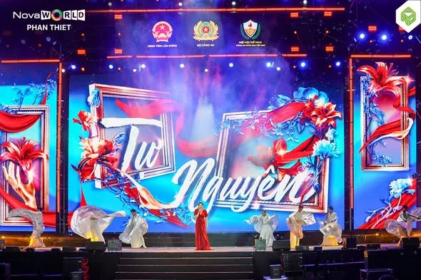 Màn LED chạy chữ “Tự Nguyện” — tên tiết mục. Vũ đoàn áo trắng dàn hai bên, ca sĩ đứng giữa sân khấu.