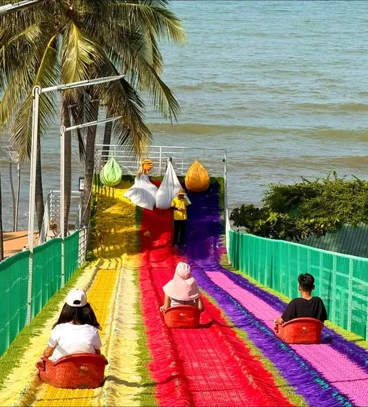 Toàn cảnh khu vui chơi: đường đua go-kart viền lốp xe, máng trượt cầu vồng và xe bus cổ dưới hàng dừa