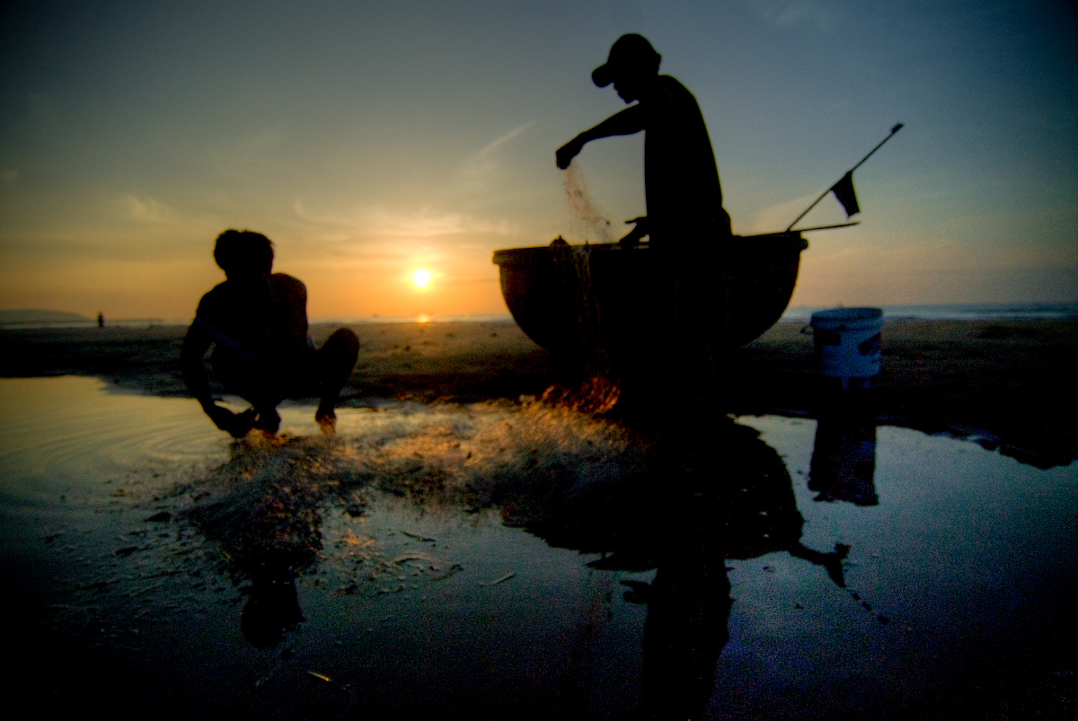 Hai ngư dân gỡ lưới trên bãi biển Phan Thiết lúc sáng sớm